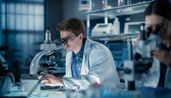 Toxicology lab technician inspecting sample under microscope
