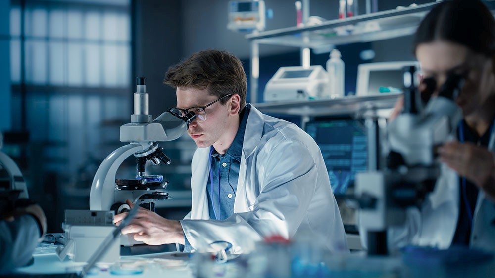 Toxicology lab technician inspecting sample under microscope