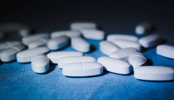 White oval shaped pills on a blue tablecloth.