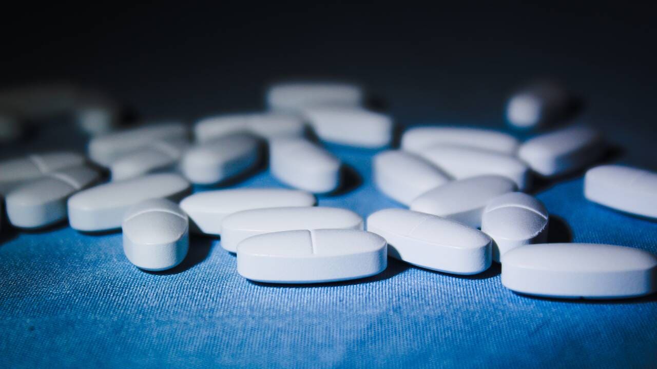 White oval shaped pills on a blue tablecloth.